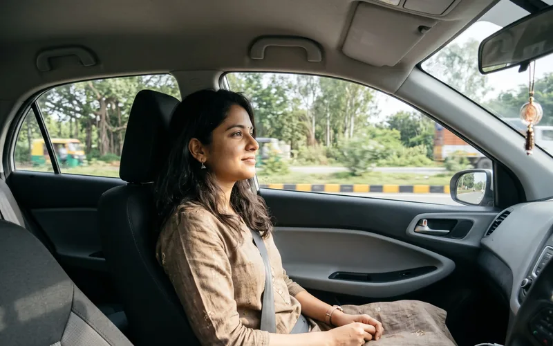 A woman in the passenger seat of a car, watching the road go by.